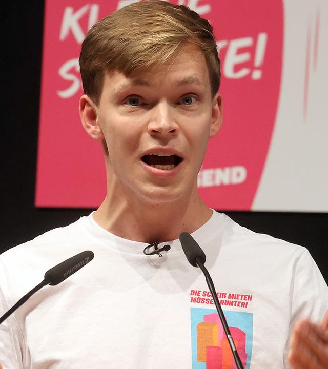 Timon Dzienus steht an einem Rednerpult und gestikuliert