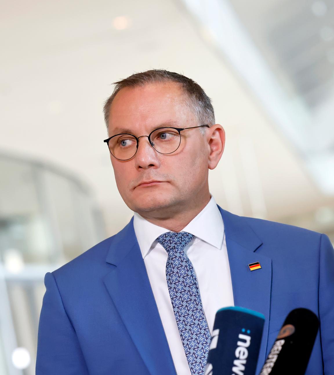Tino Chrupalla von der AfD. Er trägt einen hellblauen Anzug mit einer Deutschlandflagge als Anstecker