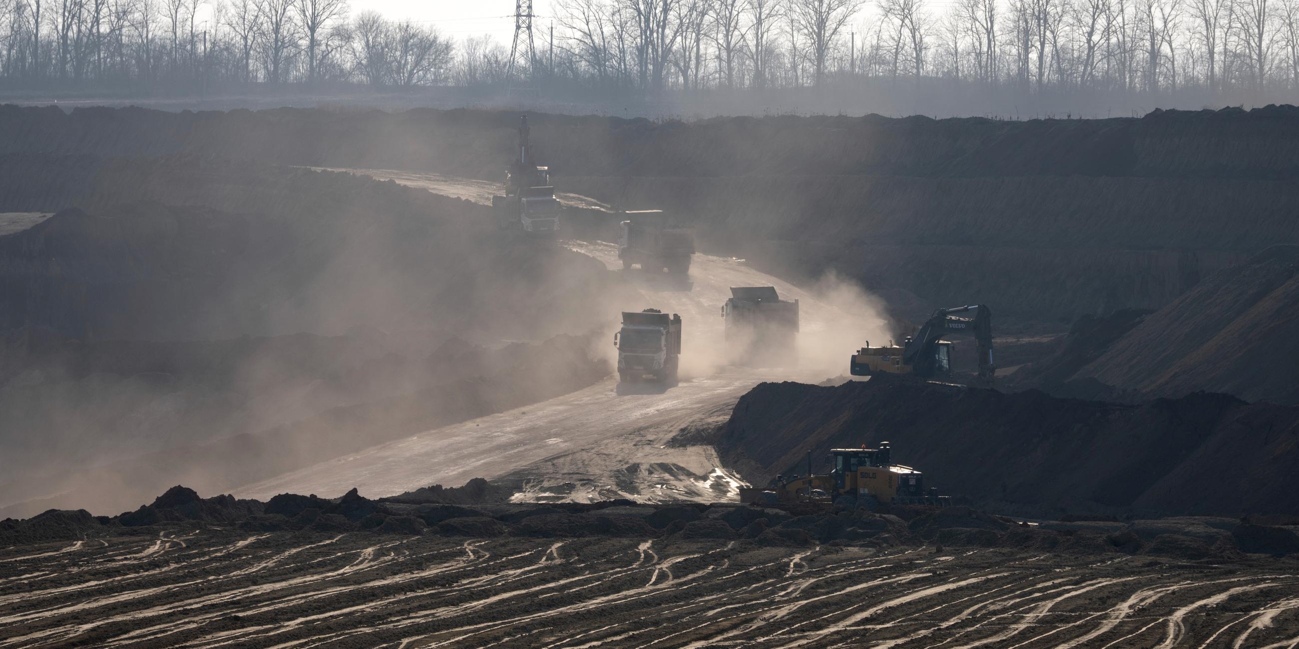 Förderfahrzeuge arbeiten in einem Ilmenit-Tagebau in einer Schlucht in der Zentralukraine. Ilmenit ist das bedeutendste Titan-Mineral.