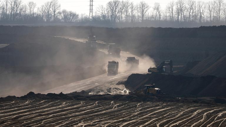 Förderfahrzeuge arbeiten in einem Ilmenit-Tagebau in einer Schlucht in der Zentralukraine. Ilmenit ist das bedeutendste Titan-Mineral.