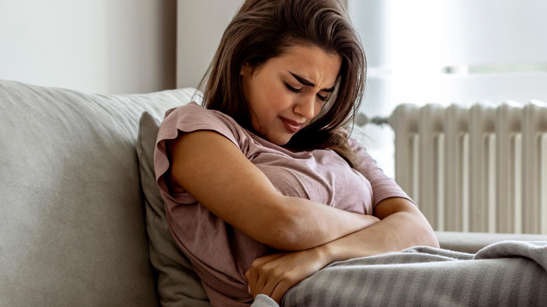 Eine Frau leidet unter Bauchkrämpfen.