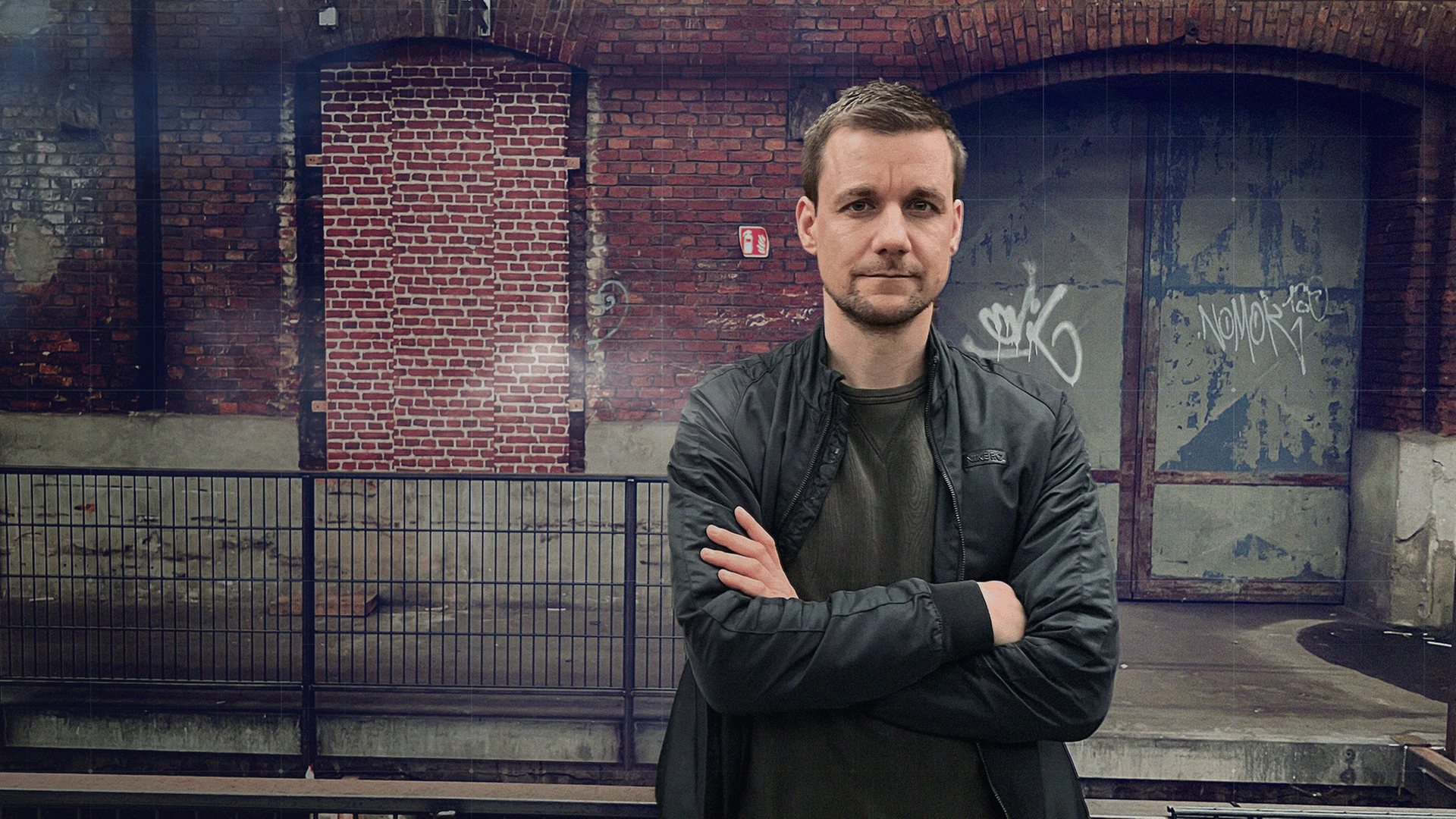 Notfallsaniäter Tobi Schlegl mit verschränkten Armen vor alter Lagerhalle