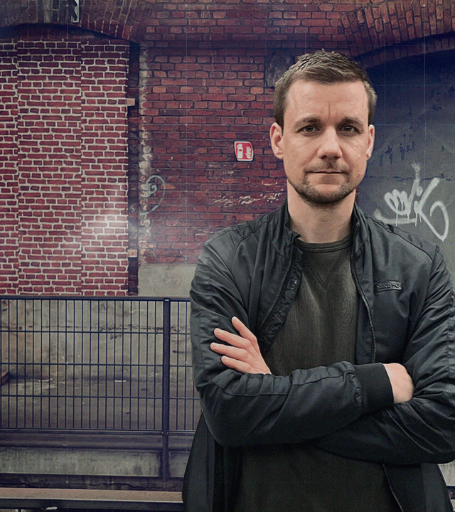 Notfallsaniäter Tobi Schlegl mit verschränkten Armen vor alter Lagerhalle