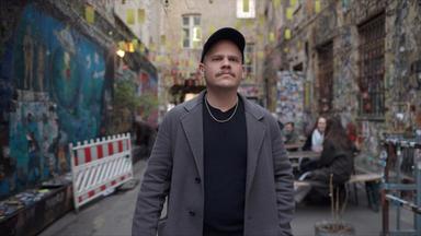 Autor und Journalist Tobias Ginsburg läuft durch eine schmale Gasse in Berlin, an den Wänden sind Graffitis.