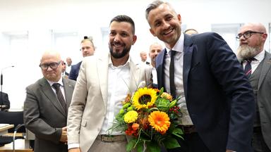 Tobias Rauch und Ulrich Siegmund lachen mit einem Blumenstrauß in der Hand
