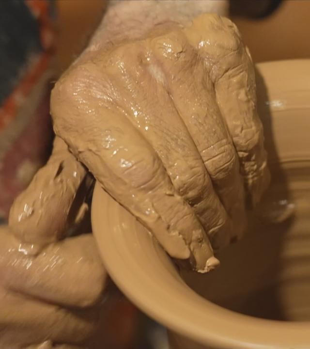 Hände eines Mannes formen dunklen Ton