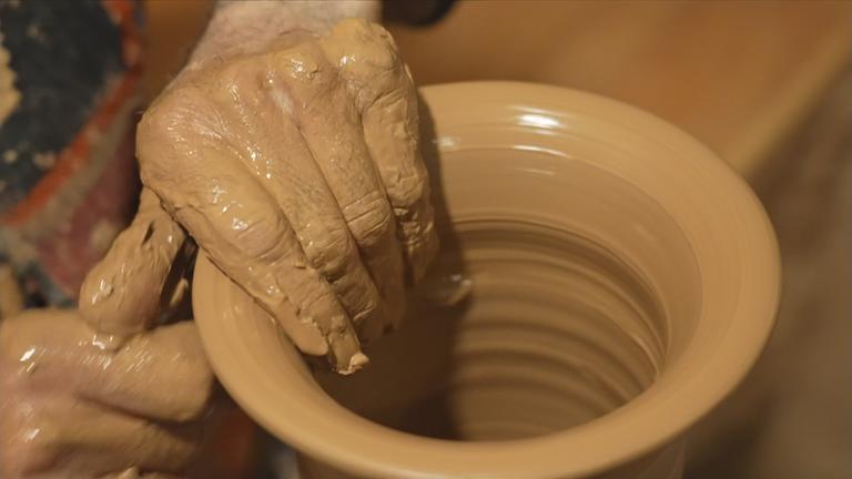 Hände eines Mannes formen dunklen Ton