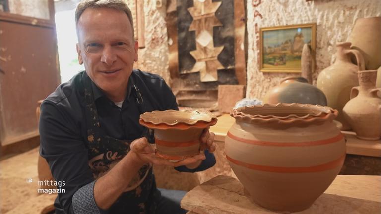 Mann hält getöpftere Objekte in die Kamera