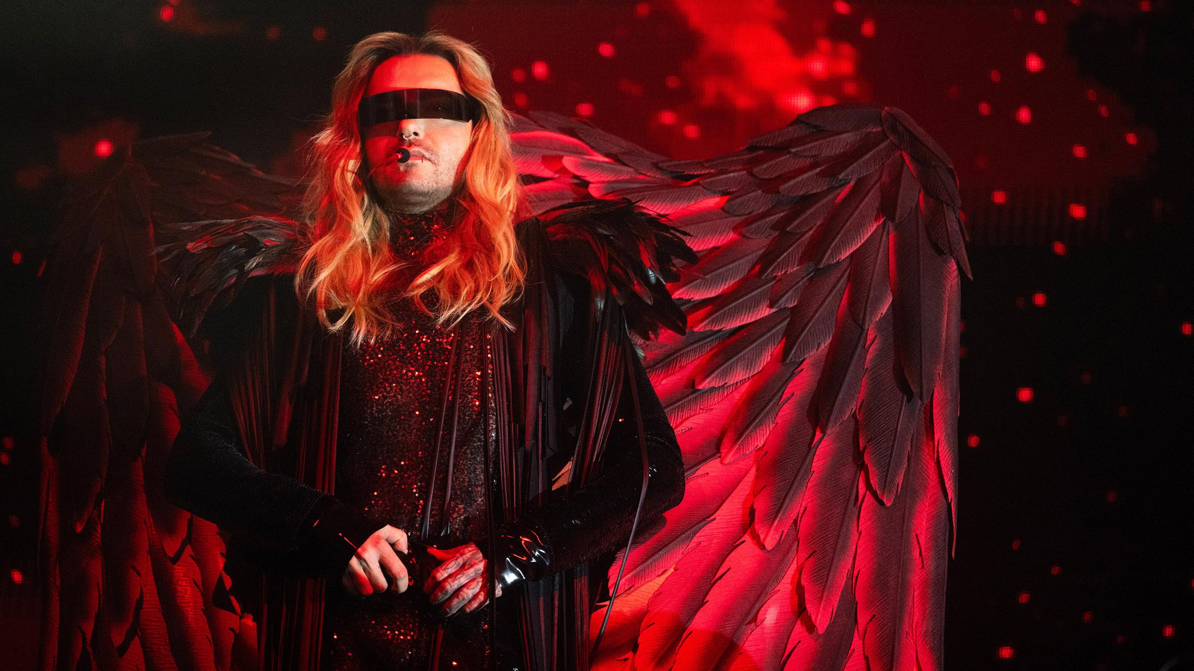 Bill Kaulitz steht mit Engelsflügeln auf einer rot belichteten Bühne beim Auftakt der Comeback-Tour von Tokio Hotel in Ludwigsburg.