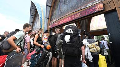Besucher des Tomorrowland-Festivals in Belgien drängen durch den Eingang zur Hauptbühne des Festivals am 17.07.2025.