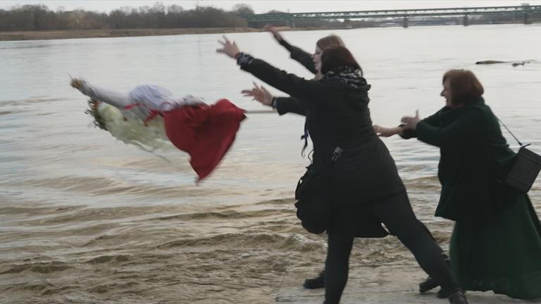 Eine Strohpuppe wird in einen Fluss geworfen