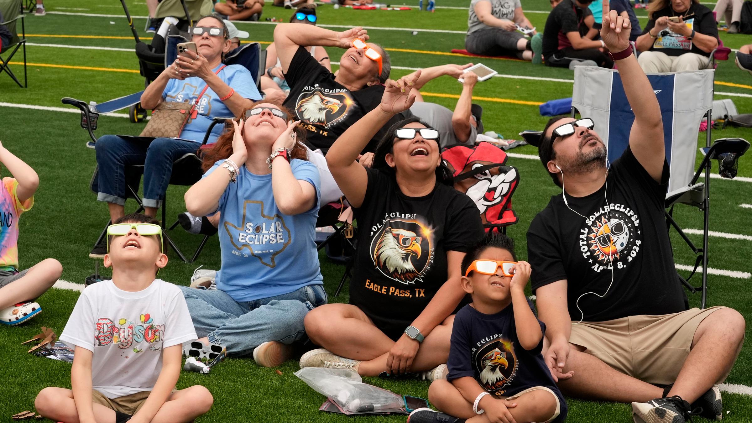 USA, Eagle Pass: Menschen beobachten, wie der Mond die Sonne während einer totalen Sonnenfinsternis teilweise verdeckt