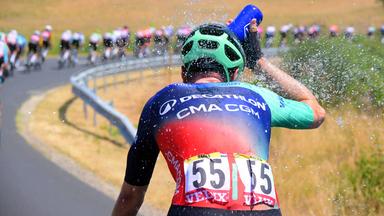 Fahrer bei der Tour de France bespritzt sich mit Wasser