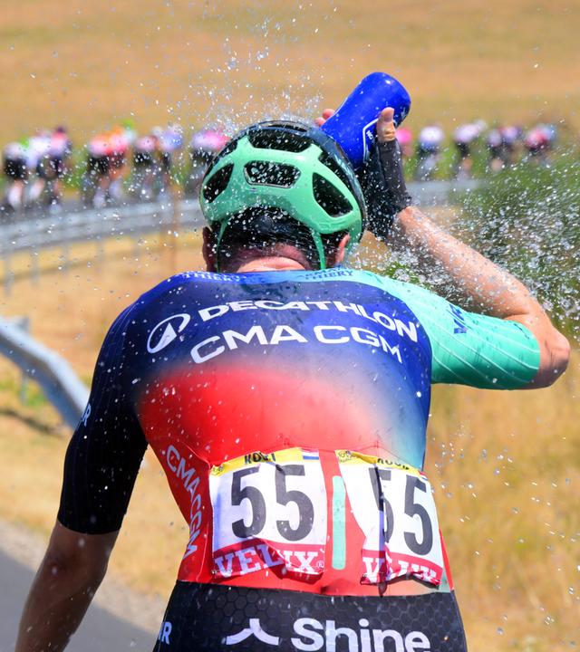 Fahrer bei der Tour de France bespritzt sich mit Wasser