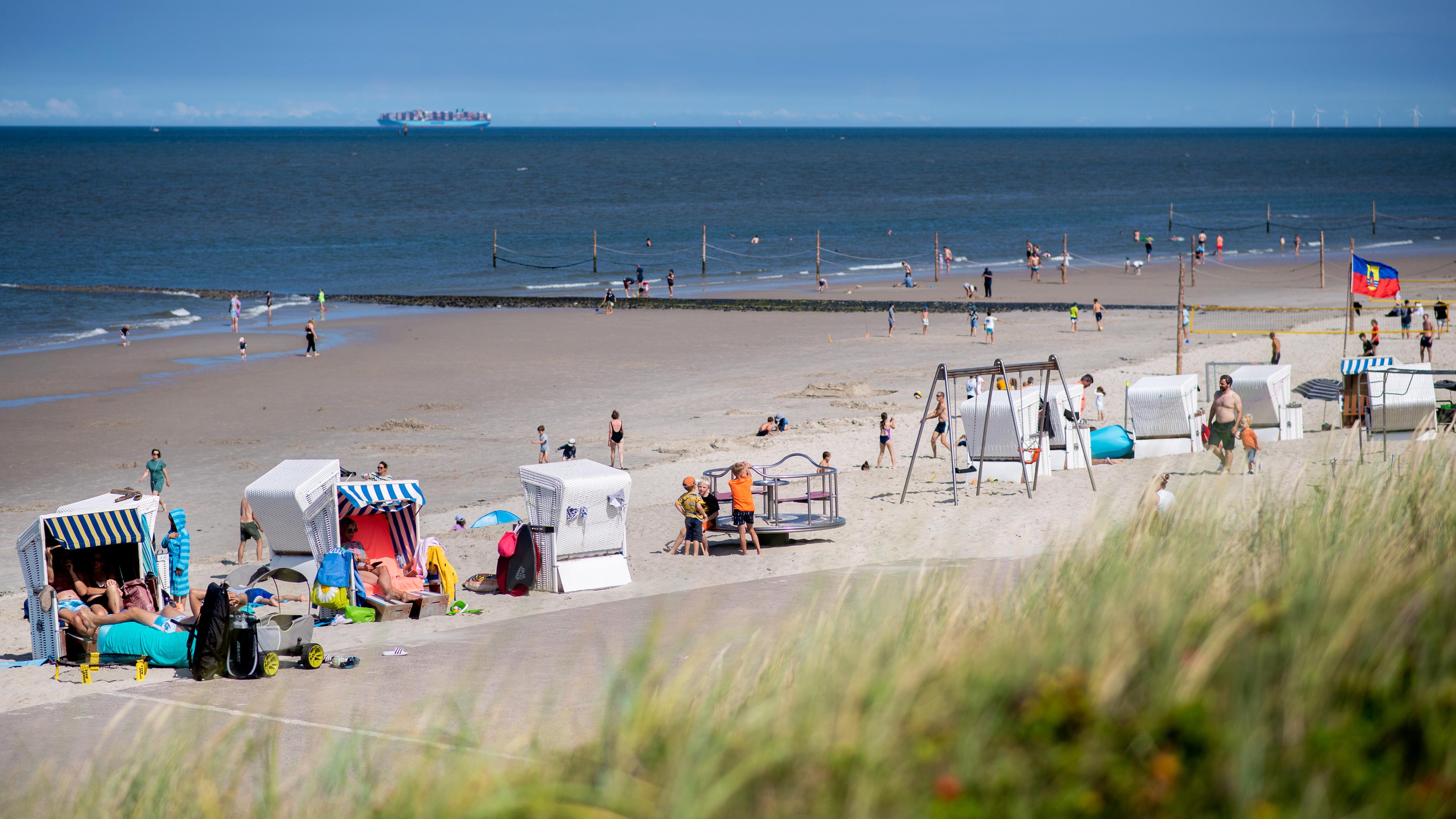 Zahlreiche Touristen sitzen bei sonnigem Wetter in Strandkörben am Strand der Insel Wangerooge