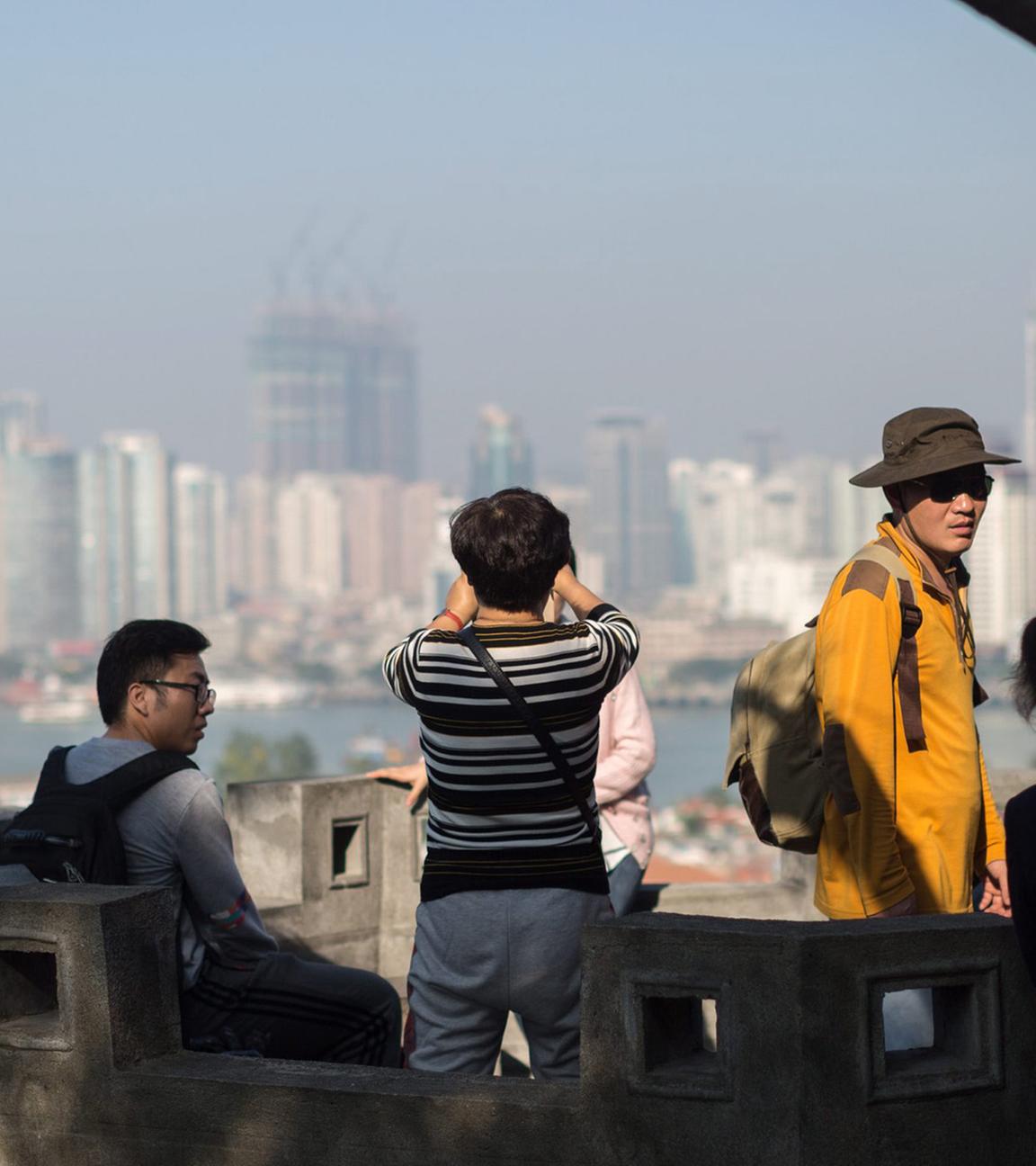Touristen genießen den Panoramablick auf alte  Wohngebäude auf der Insel Gulangyu im Vordergrund und die moderne Skyline der Insel Xiamen im Hintergrund, Provinz Fujian, China. (Archivbild)