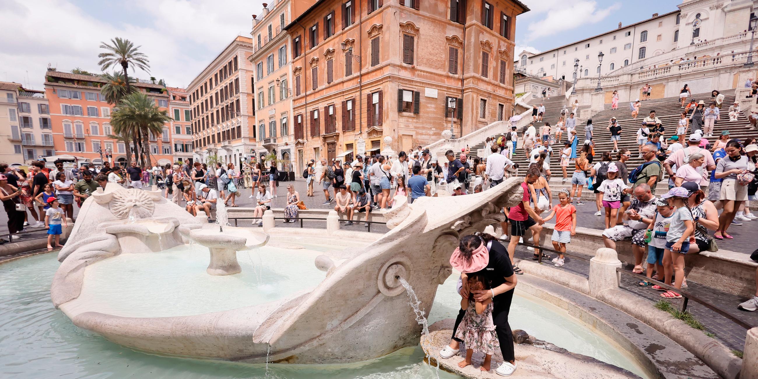 In Rom kühlen sich Touristen und Bewohner in einem Springbrunnen ab.