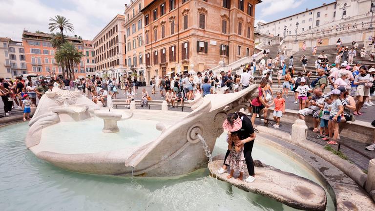 In Rom kühlen sich Touristen und Bewohner in einem Springbrunnen ab.