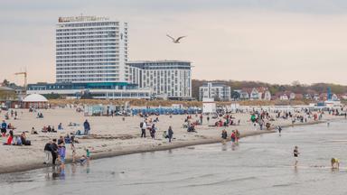 Menschen genießen milde Temperaturen am Strand von Warnemünde in Rostock, Mecklenburg-Vorpommern, am 18.04.2026.