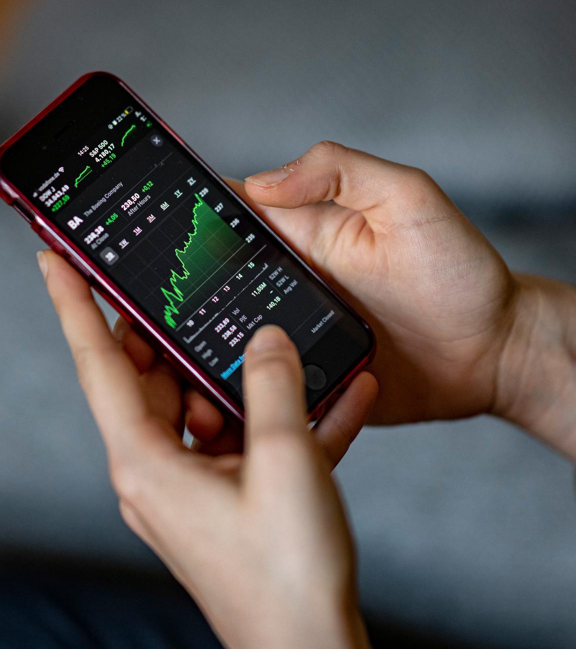 Ein Mensch schaut sich eine Aktie auf dem Smartphone an.
