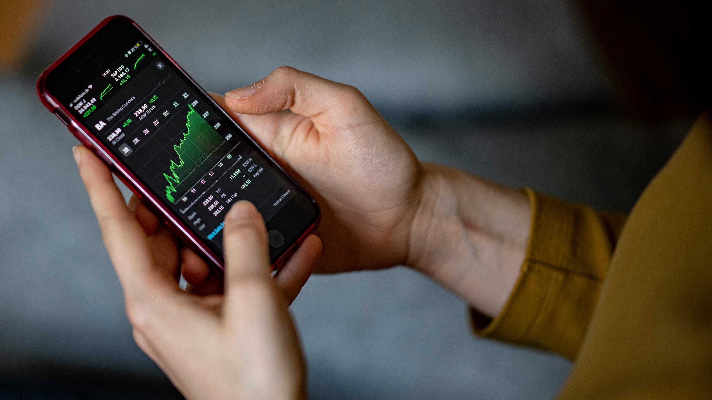 Ein Mensch schaut sich eine Aktie auf dem Smartphone an.