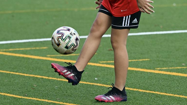 Fußballplatz mit Spielerinn die Ball kickt