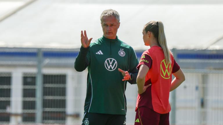 v.li. Bundestrainer Christian Wueck und Spielerin Marie Mueller sprechen miteinander auf dem Trainingsplatz.