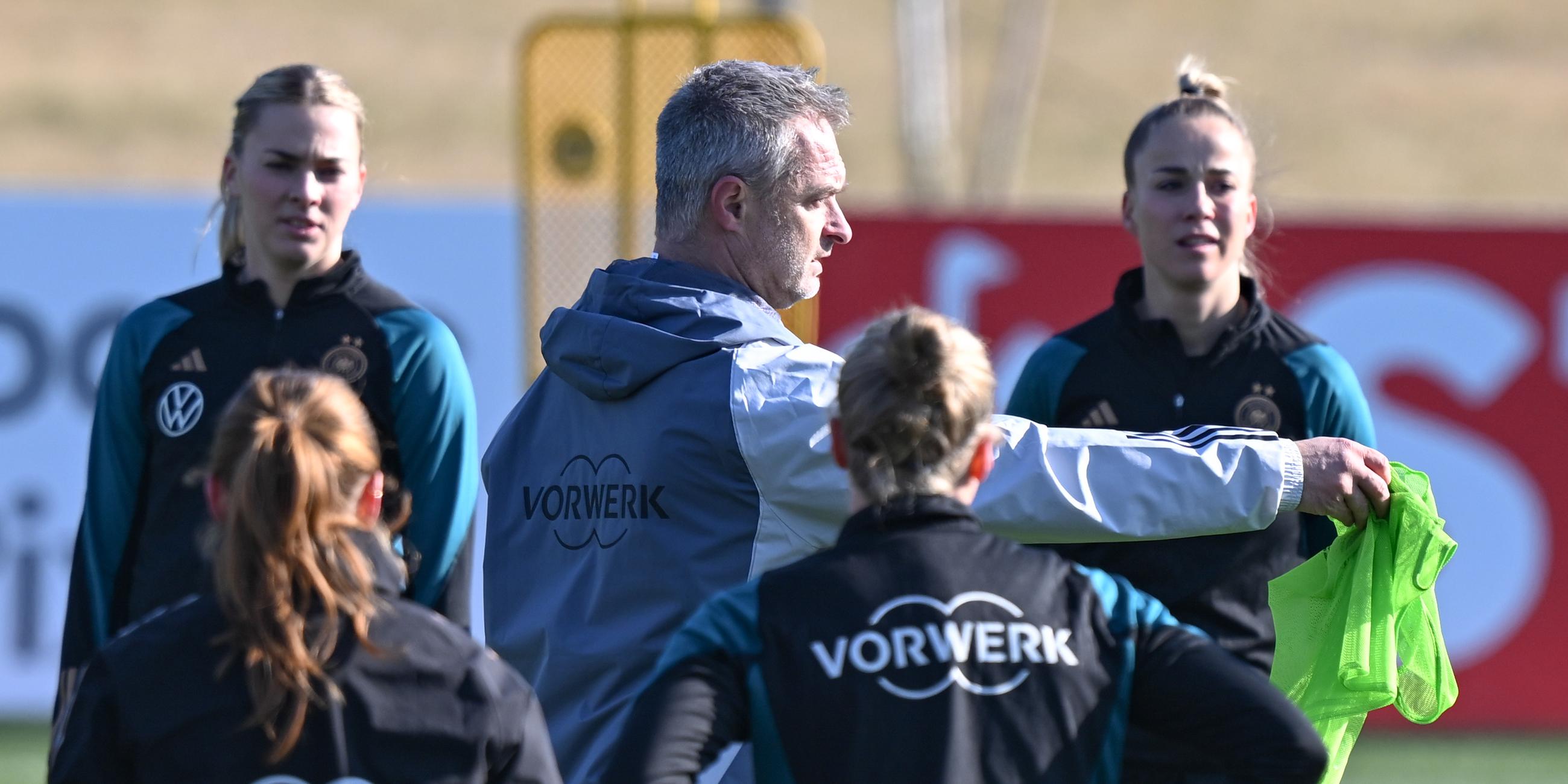 Hessen, Frankfurt/Main: Bundestrainer Christian Wück (M) spricht beim Training der Frauen-Nationalmannschaft auf dem DFB-Campus zu den Nationalspielerinnen um die neue Kapitänin Giulia Gwinn (r).
