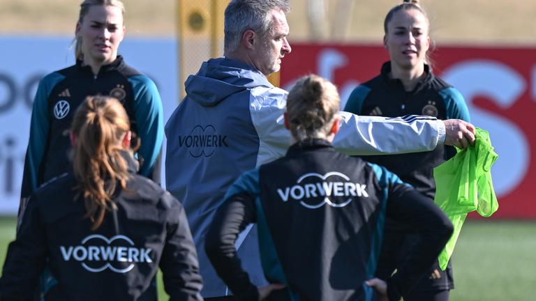 Hessen, Frankfurt/Main: Bundestrainer Christian Wück (M) spricht beim Training der Frauen-Nationalmannschaft auf dem DFB-Campus zu den Nationalspielerinnen um die neue Kapitänin Giulia Gwinn (r).