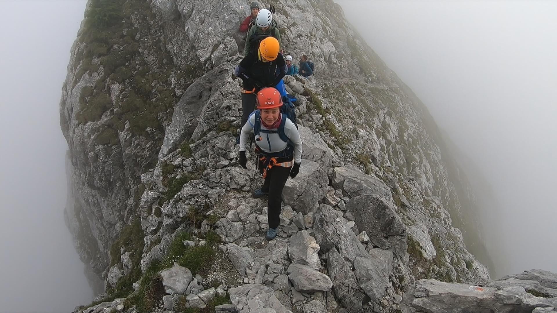 Auf dem Bild sind die Bergsteigerinnen auf einem schmalen Grat in der Höhe zu sehen.