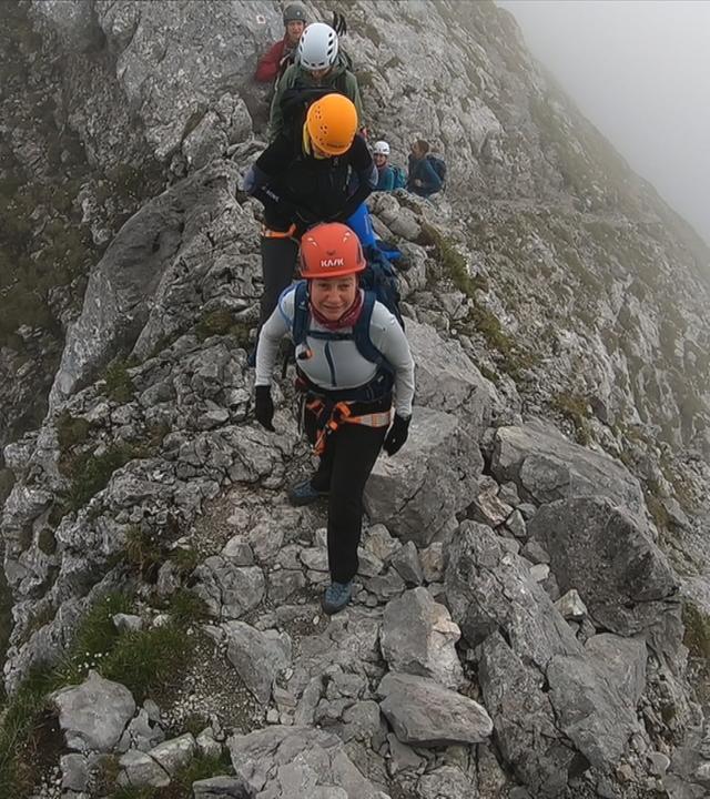 Auf dem Bild sind die Bergsteigerinnen auf einem schmalen Grat in der Höhe zu sehen.