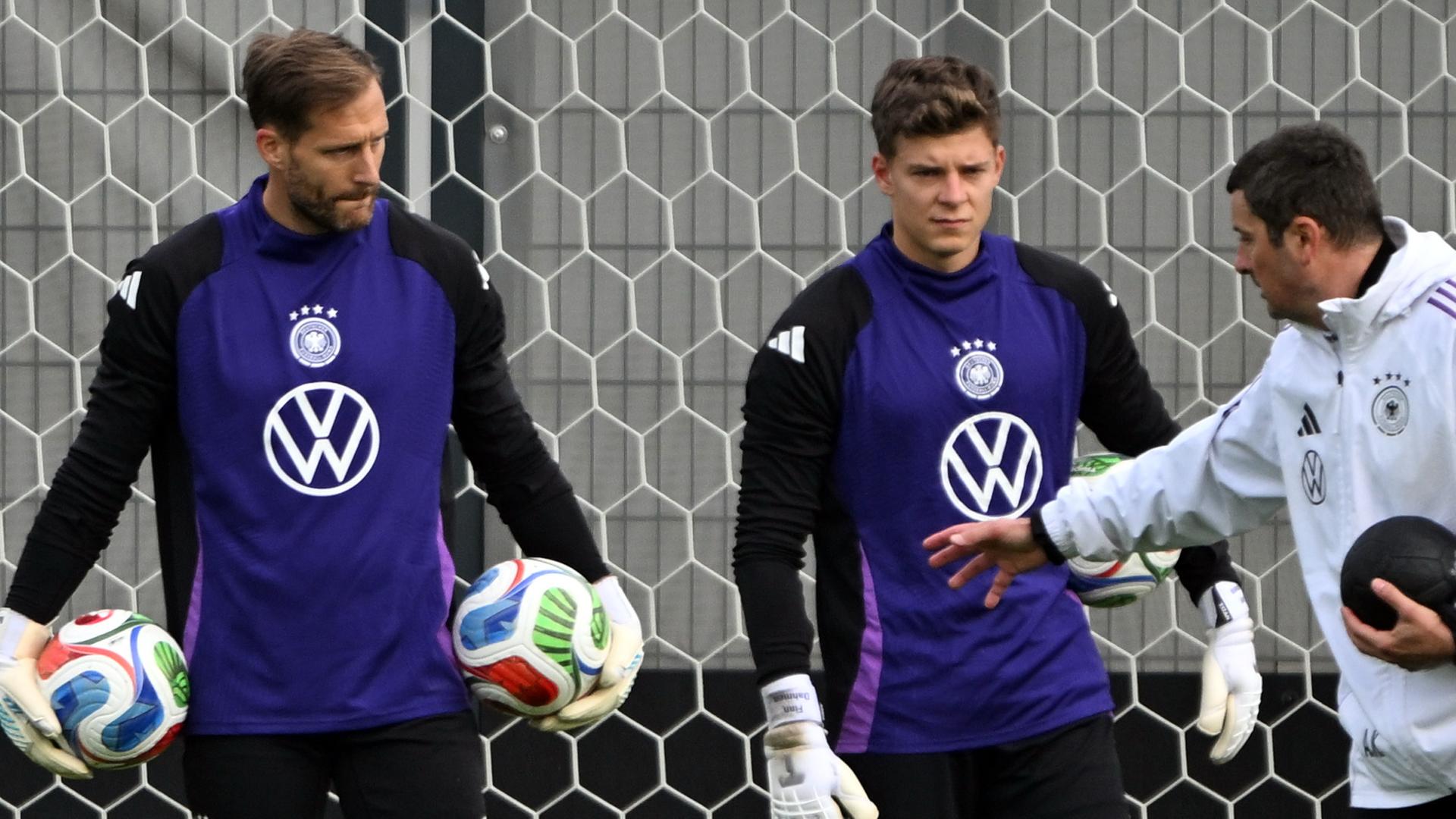 Torwarttrainer Andreas Kronenberg (l) spricht während des Trainings mit Torwart Oliver Baumann und Torwart Finn Dahmen