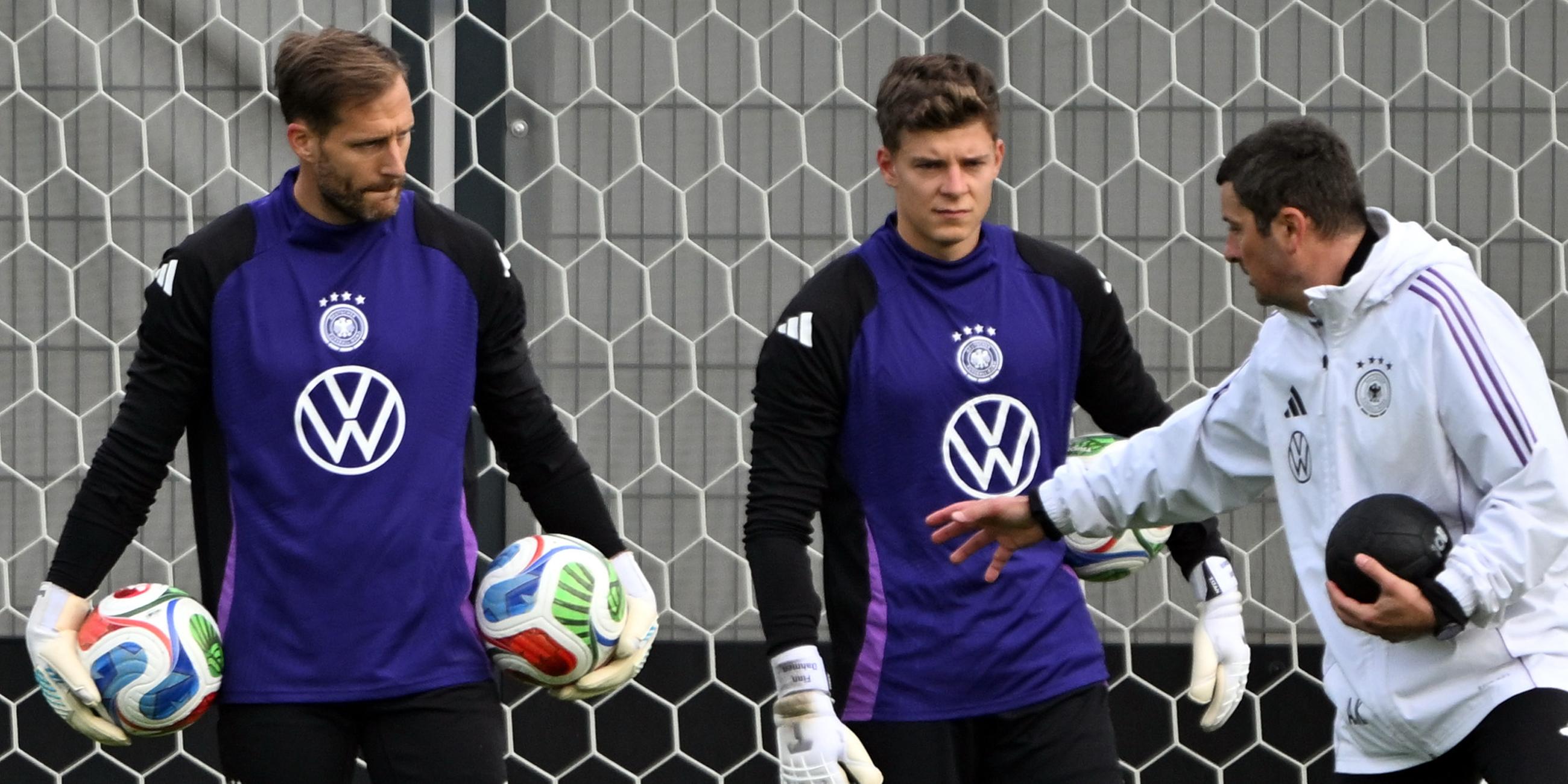 Torwarttrainer Andreas Kronenberg (l) spricht während des Trainings mit Torwart Oliver Baumann und Torwart Finn Dahmen