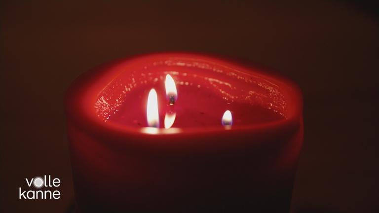 Eine brennende rote Kerze mit drei Dochten.