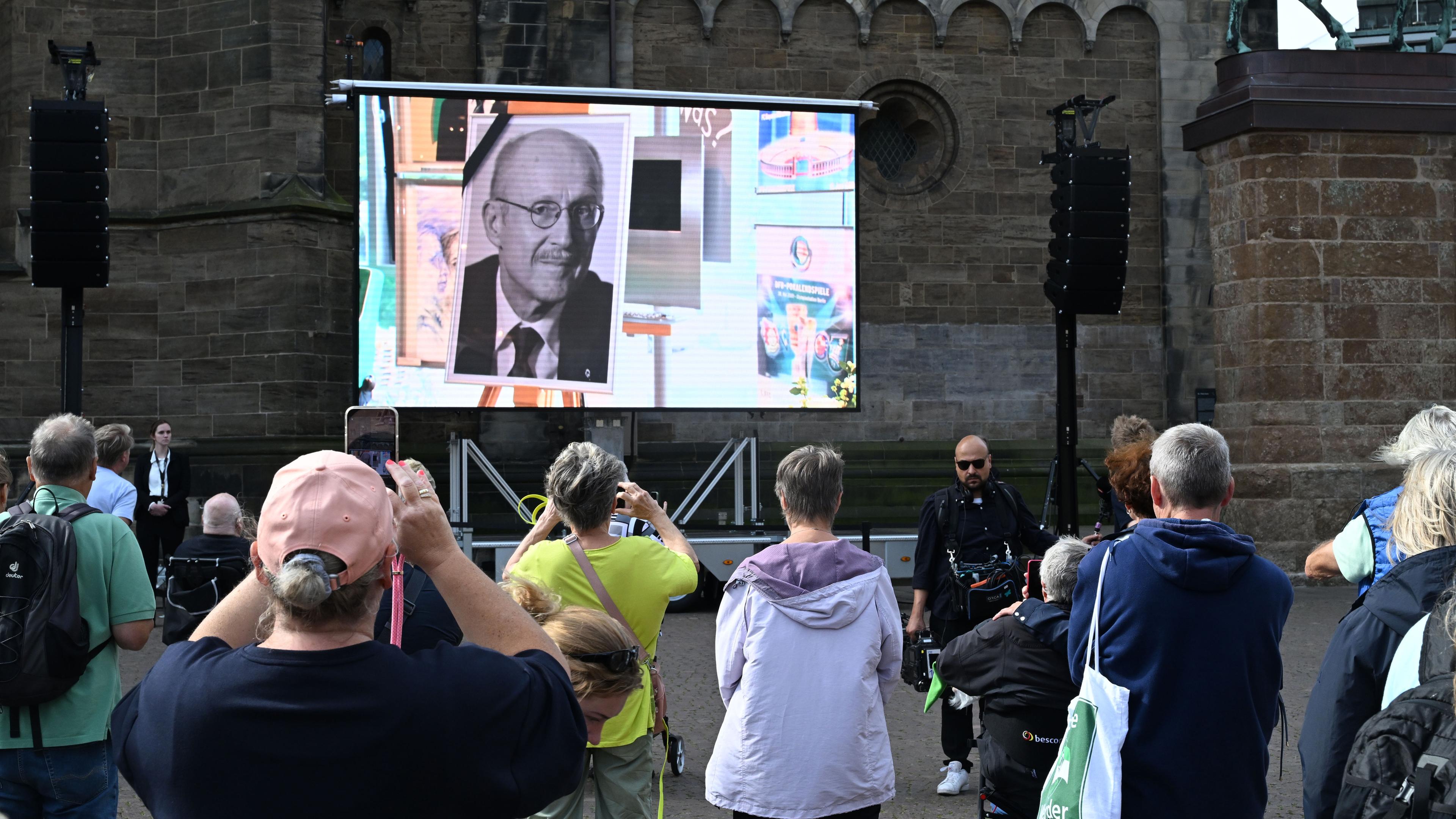 Bremen: Menschen nehmen an der Trauerfeier für Willi Lemke teil, die live vor dem Bremer Dom übertragen wird. 