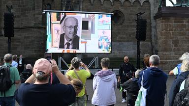 Bremen: Menschen nehmen an der Trauerfeier für Willi Lemke teil, die live vor dem Bremer Dom übertragen wird. 