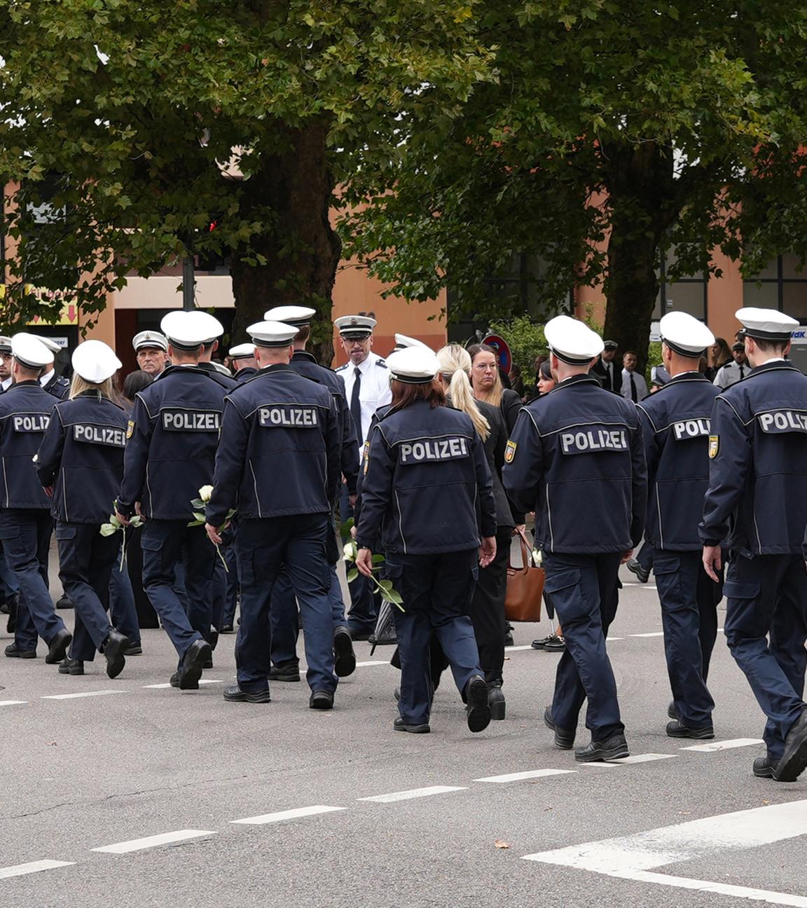 30.08.2025, Saarland, Saarlouis: Polizisten gehen vor dem Trauergottesdienst für den in Völklingen erschossenen Polizisten,  Polizeioberkommissar Simon B., auf der Straße.