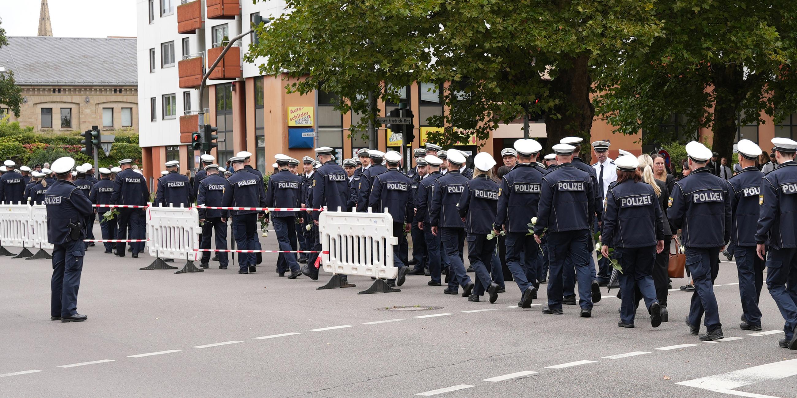 30.08.2025, Saarland, Saarlouis: Polizisten gehen vor dem Trauergottesdienst für den in Völklingen erschossenen Polizisten,  Polizeioberkommissar Simon B., auf der Straße.