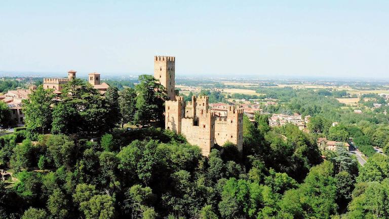 Die mittelalterliche Burg Rocca Viscontea liegt auf einem bewaldeten Hügel.