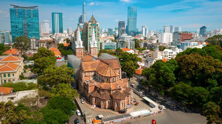 Aufnahme der Notre-Dame Kirche in Saigon vor der Skyline der Stadt