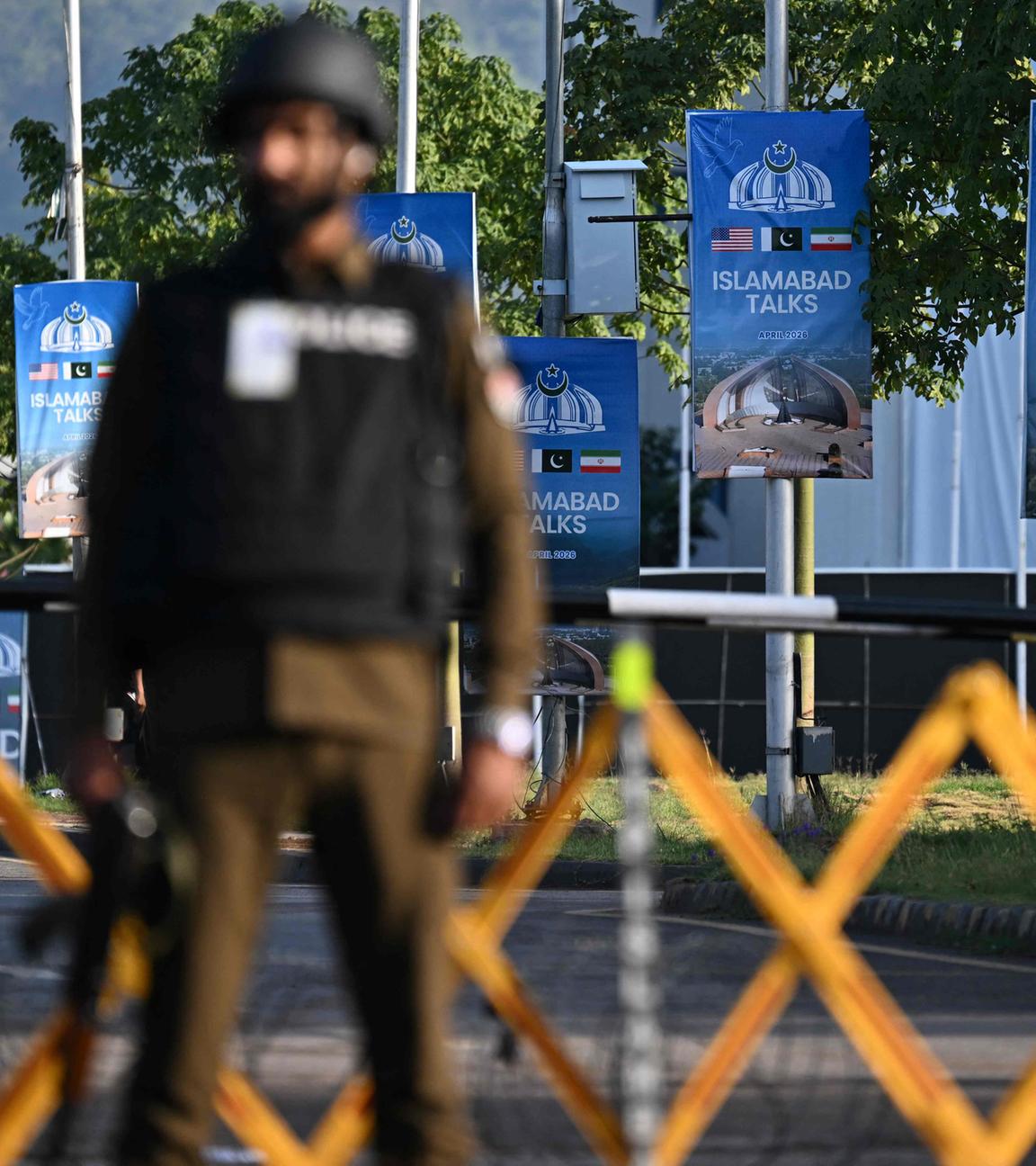Ein Polizist steht in der Nähe des Serena Hotels im sogenannten "Red Zone" -Viertel in Islamabad Wache neben Plakaten.