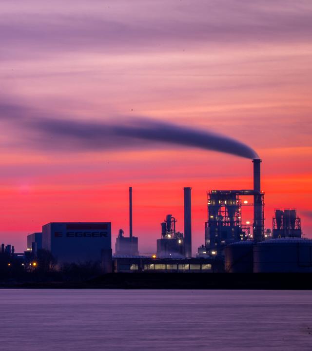 Mecklenburg-Vorpommern: Wismar: Dampf steigt aus Schornsteinen vor einem rosa verfärbten Abendhimmel.