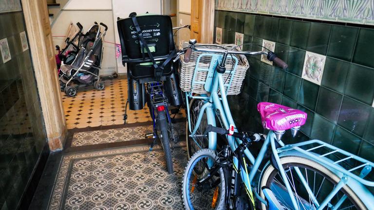 Fahrräder und Kinderwagen stehen im Eingangsbereich eines Hausflurs.