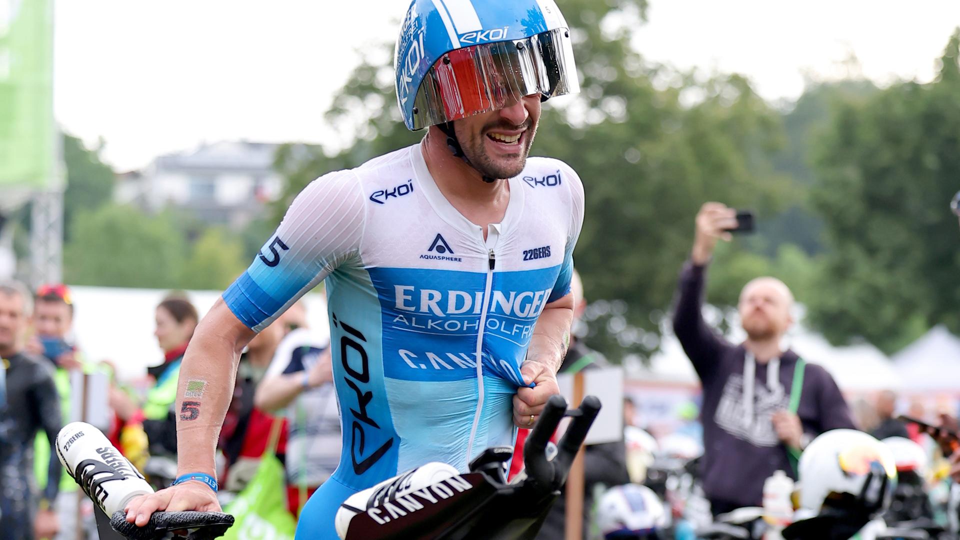 Patrick Lange läuft mit dem Fahrrad in der Wechselzone.