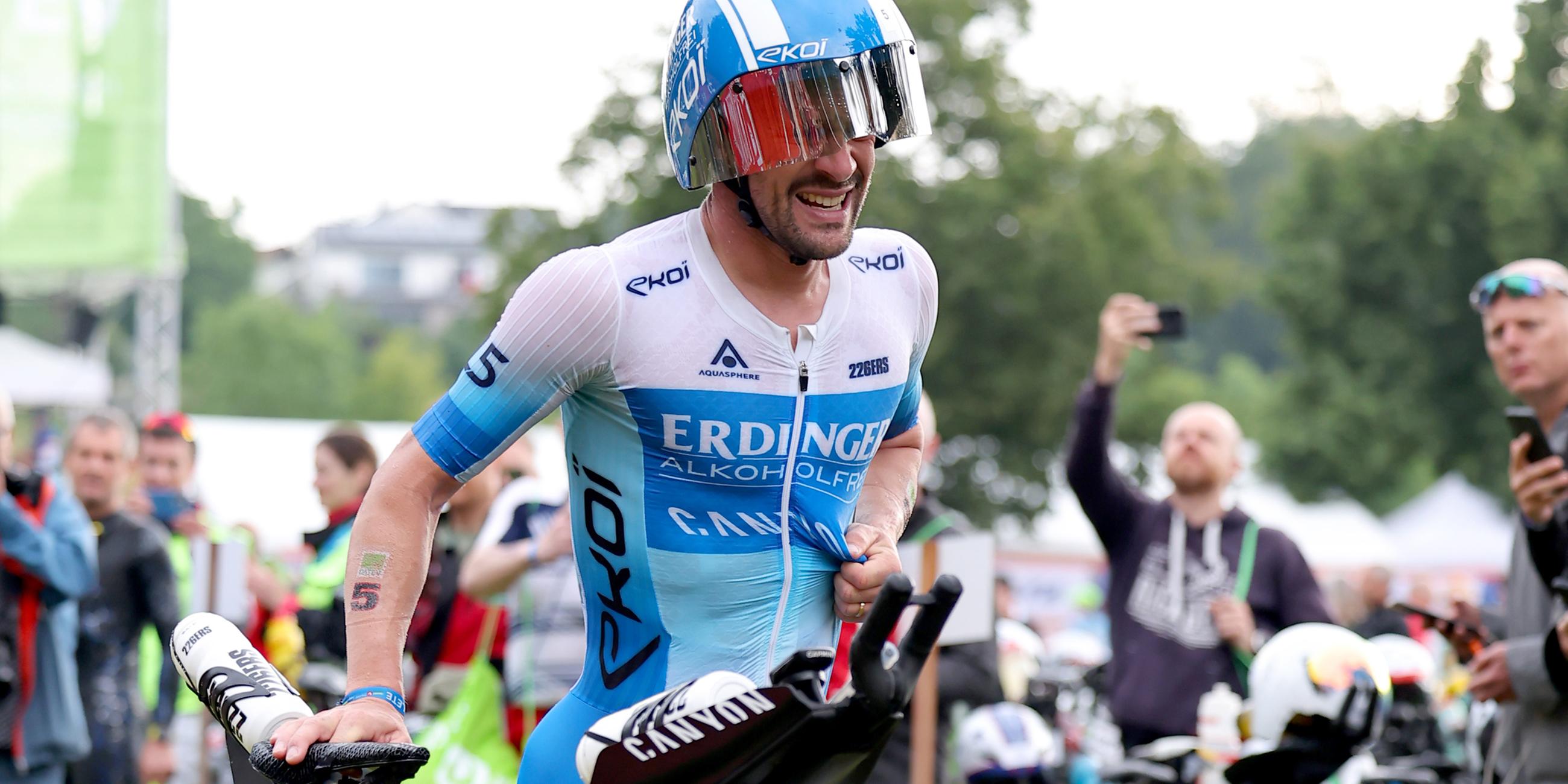Patrick Lange läuft mit dem Fahrrad in der Wechselzone.