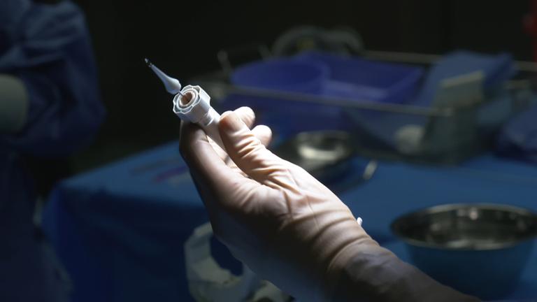 Ein Arzt im Operationssaal hält den Katheter zurm Einsatz des Klappenersatzes.