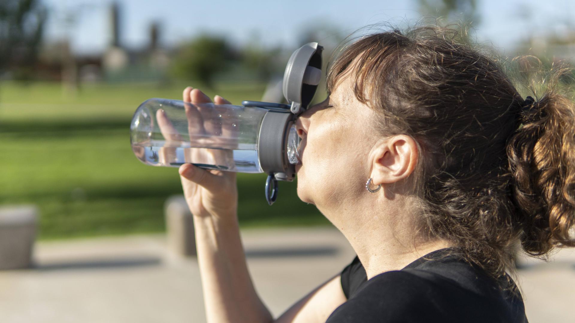 Eine Frau trinkt aus einer Trinkflasche.