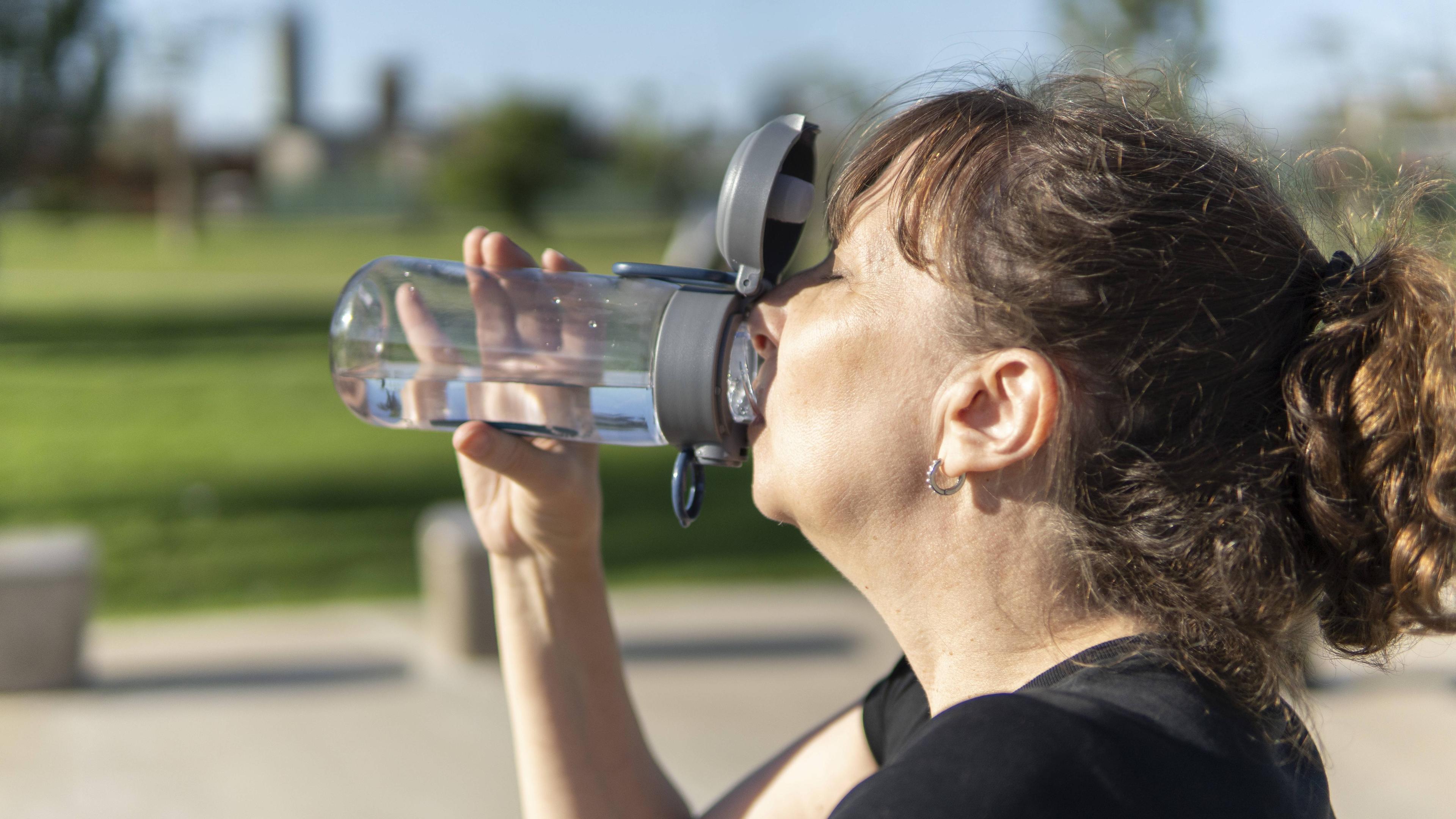 Eine Frau trinkt aus einer Trinkflasche.