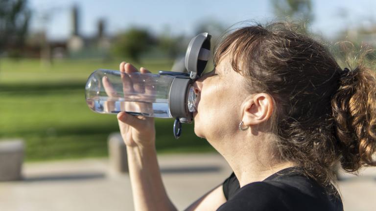 Eine Frau trinkt aus einer Trinkflasche.
