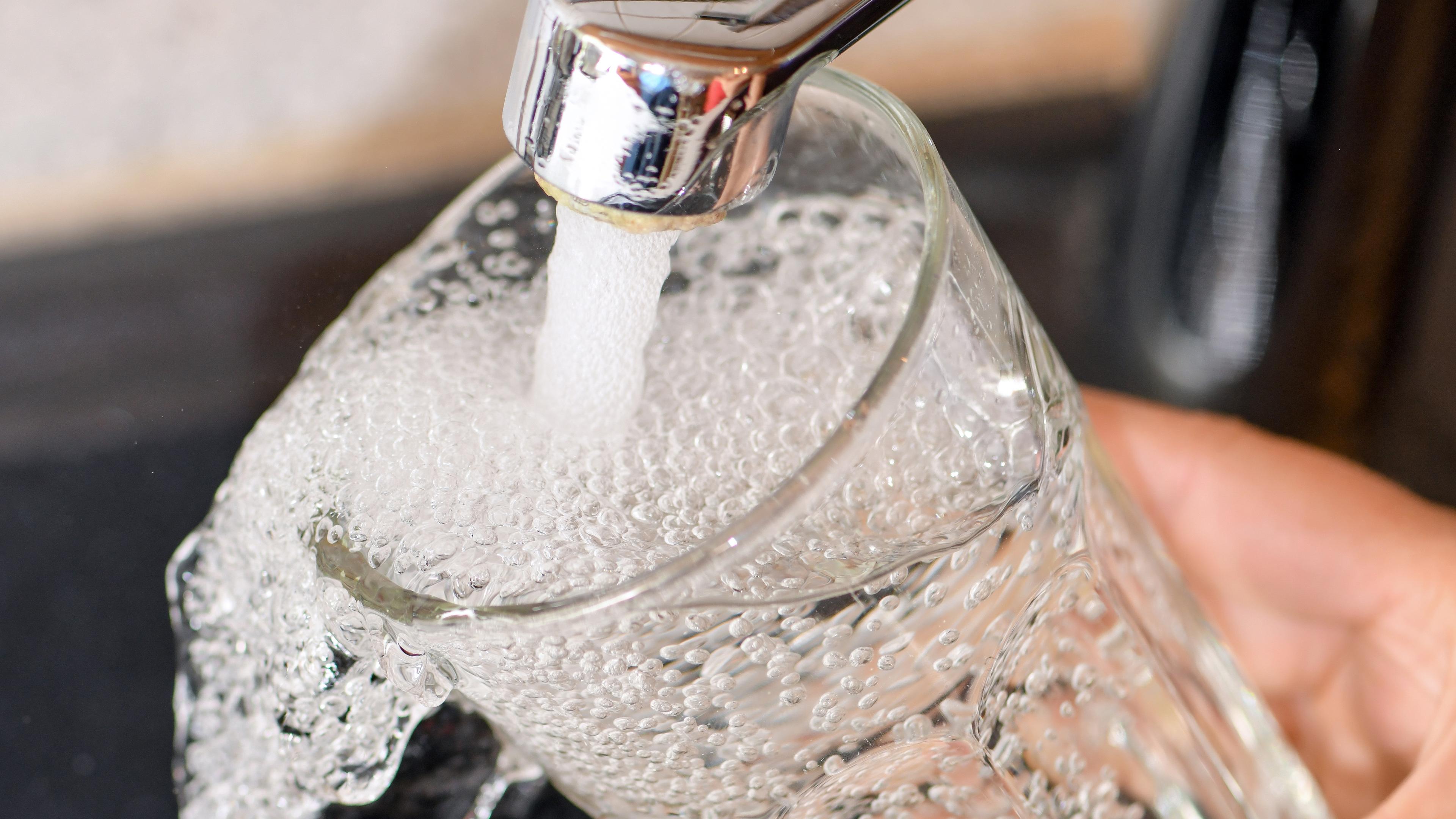 Frau füllt Glas mit Trinkwasser